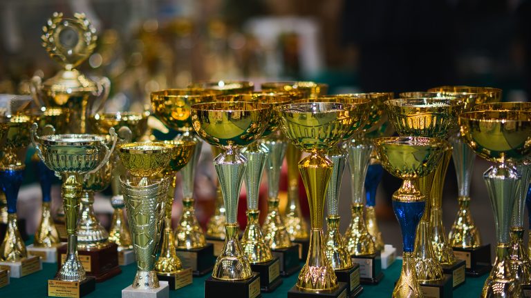 Zestaw złotych trofeów na stole, symbolizujący zwycięstwo i osiągnięcie