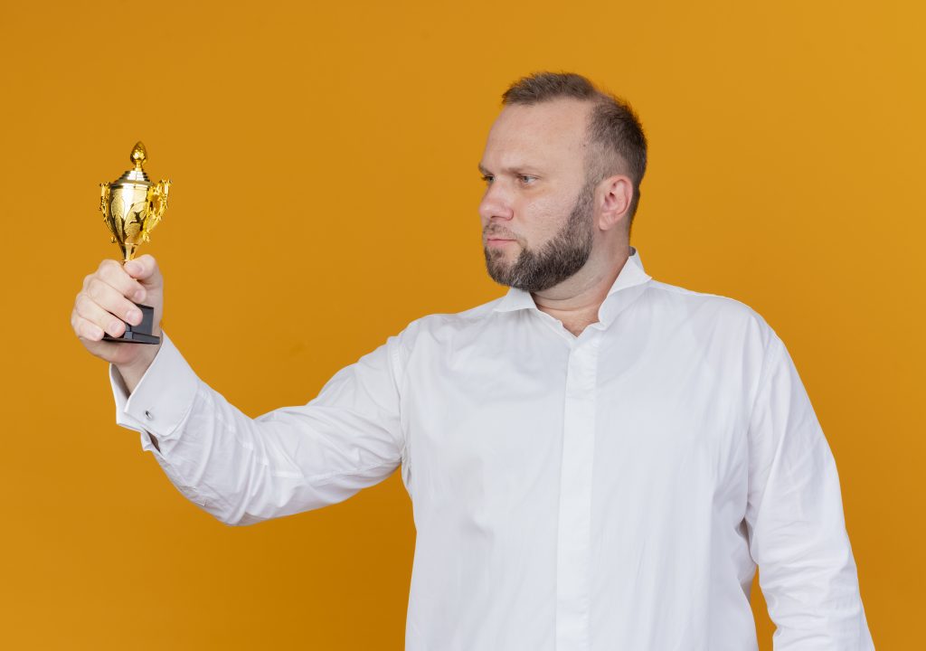 Brodaty mężczyzna w białej koszuli trzyma trofeum